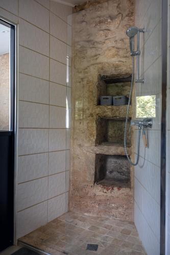 La salle de bains est pourvue d'une douche et d'un mur en pierre. dans l'établissement La petite bergerie, à Biard