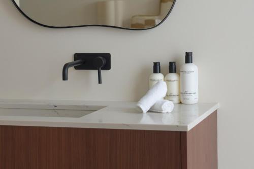 a bathroom counter with three bottles of soap and a mirror at SHWAY - The Proof Reader in Antwerp