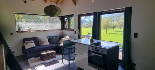 un salon avec un canapé et une cuisine avec des fenêtres dans l'établissement Cabane dans la vallée de Chamonix, à Servoz