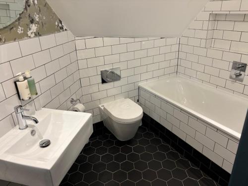 a bathroom with a sink and a toilet and a tub at The Red Lion Hotel in London