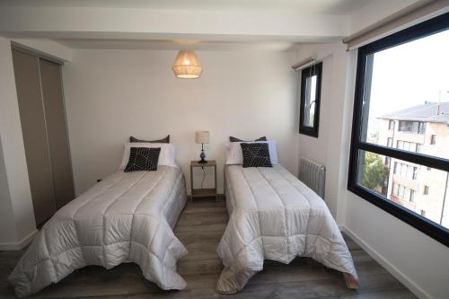 two beds in a room with a window at Espacio nuevo, tranquilo y céntrico en Bariloche in San Carlos de Bariloche