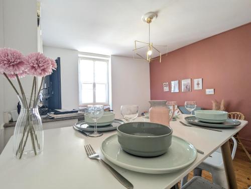une table avec un bol et des assiettes et un vase avec des fleurs dans l'établissement La salle de jeux-3 chambres-5pers-cnpe bugey, à Ambérieu-en-Bugey