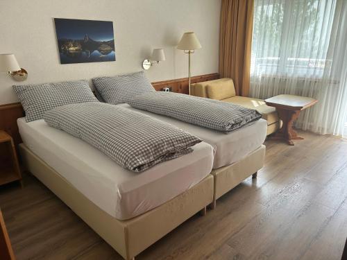 um quarto de hotel com duas camas e uma cadeira em Hotel Adonis em Zermatt