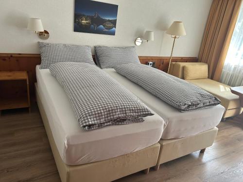uma cama com dois travesseiros em um quarto em Hotel Adonis em Zermatt