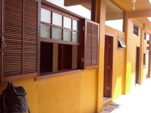 a yellow building with windows and a black purse at Trindade Hospeda - Casas na Praia dos Ranchos in Trindade