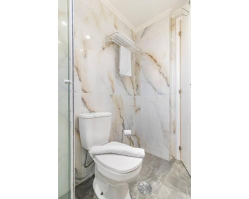 a bathroom with a toilet and a glass shower at H4 La Residence Paulista in Sao Paulo
