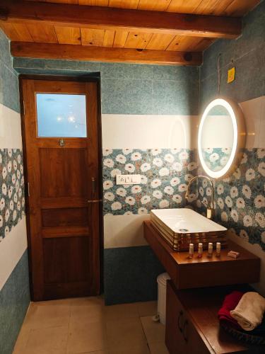 a bathroom with a door and a sink and a mirror at Woody Trails - Astronomy, Graphology, Family, Kainchi Dham in Bhowāli