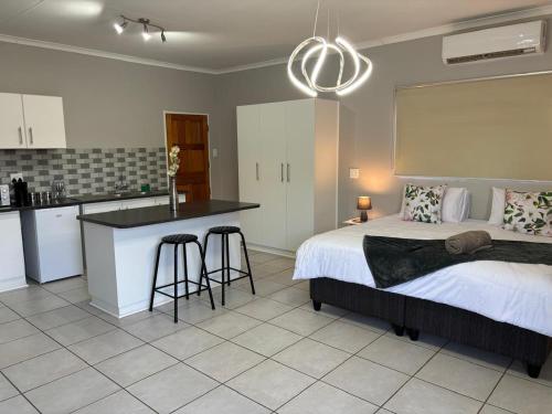 a bedroom with a bed and a kitchen with a counter at Carstens Garden Cottages in Kimberley