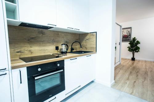 a kitchen with white cabinets and a black oven at Apartament Bellissima in Bielsko-Biala