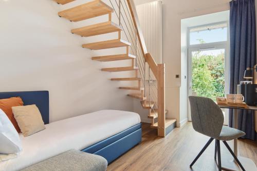 a bedroom with a staircase and a chair at Les Maisons de Tatihou, The Originals Relais in Saint-Vaast-la-Hougue