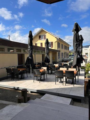 a patio with tables and chairs and umbrellas at Buffet de la gare Courtelary in Courtelary