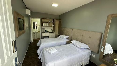 a bedroom with two beds and a bathroom at John- R Apart-hotel Curitiba Jardim Botânico in Curitiba