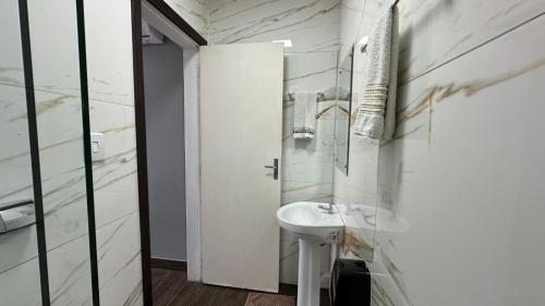 a white bathroom with a sink and a mirror at John- R Apart-hotel Curitiba Jardim Botânico in Curitiba