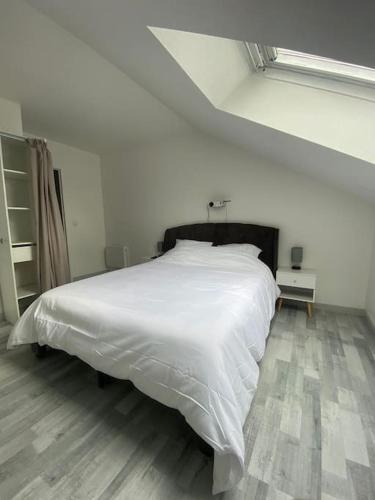 Cette chambre comprend un grand lit blanc et du parquet. dans l'établissement Appartement morangis, à Savigny-sur-Orge