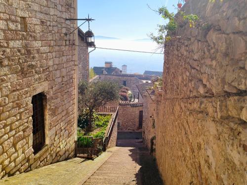 an alley between two brick buildings with a city in the background at A 6 minuti da San Carlo Acutis - LA SUITE DI SAN RUFINO, Centralissimo, 2 Letti Matrimoniali, Spazioso, Perfetto - La nostra Forza è la Presenza 24-7, MyAssisiSuite, più di un semplice Appartamento - MÓWIMY PO POLSKU in Assisi