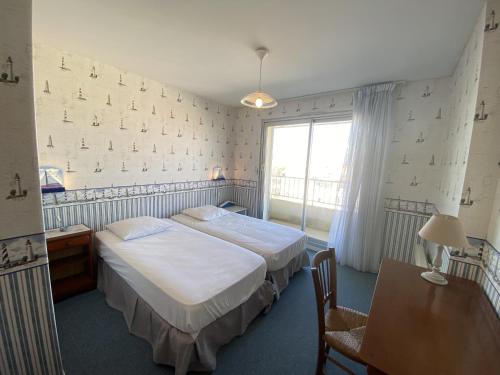 une chambre avec deux lits et une table et une fenêtre dans l'établissement Bel Appartement face mer - GARAGE, à Les Sables-dʼOlonne