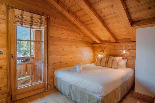 Ce lit se trouve dans une chambre en bois dotée d'une fenêtre. dans l'établissement Maison Neuve 3 - Proche des pistes - Vue, aux Houches