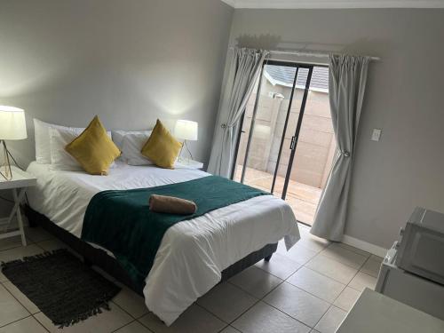 a bedroom with a bed and a door to a patio at Carstens Garden Cottages in Kimberley