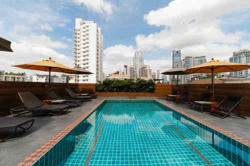 a swimming pool with chairs and umbrellas on a building at The Dawin Hotel in Bangkok