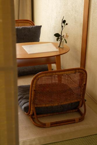 a table with a wicker chair and a table with a plant at Kanzaki Beach House in Kanzaki