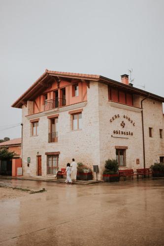 two people standing outside of a building in the rain at Casa Rural Osingain in Caicedo Yuso