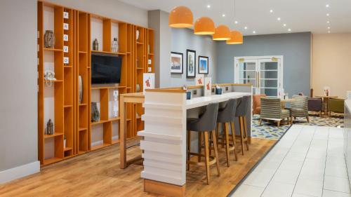 a kitchen with a bar with stools and a tv at Holiday Inn Rotherham-Sheffield M1,Jct.33 by IHG in Rotherham