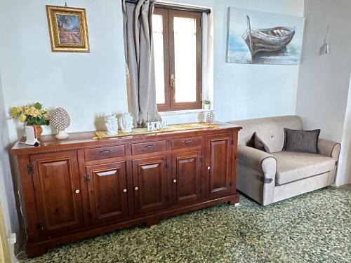 a living room with a wooden cabinet and a chair and a window at Al Vicoletto House in Forza dʼAgro