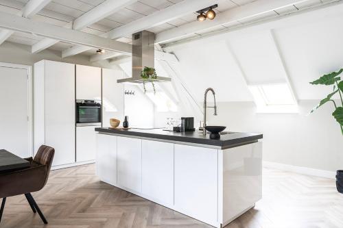 a kitchen with white cabinets and a black counter top at Xxl Loft City Center Villa Tilburg Willem 2 in Tilburg