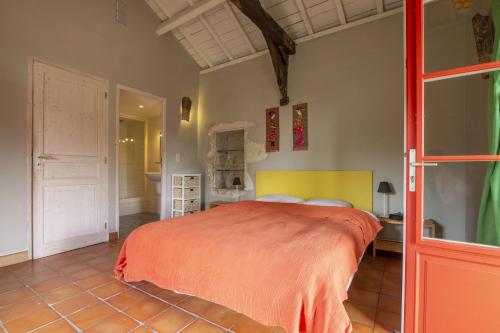 a bedroom with a large bed with an orange blanket at Labouysse in Montcuq