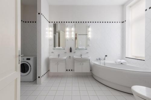a white bathroom with a tub and a sink and a washing machine at K1820 Family apartments in Rīga