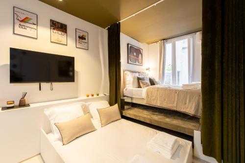 une chambre avec un lit et une télévision sur un mur dans l'établissement Room Aboukir, Paris Centre, à Paris