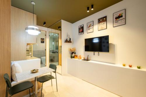 un salon avec une table et une télévision au mur dans l'établissement Room Aboukir, Paris Centre, à Paris