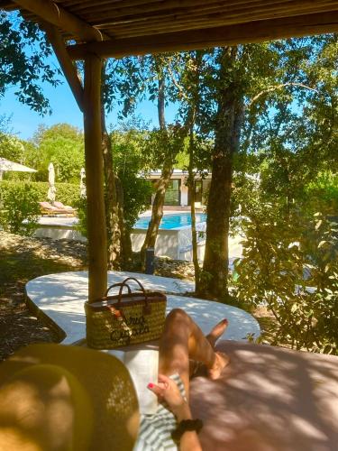 une personne assise sur une table près d'une piscine dans l'établissement Aria Cigala, à Bonifacio