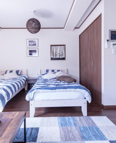 two beds in a bedroom with white walls and wooden floors at Dain Hostel1 in Tokyo