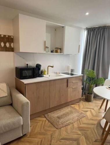 une cuisine avec un évier et un micro-ondes dans l'établissement La Siesta - Jacuzzi et Cozy, à Cholet