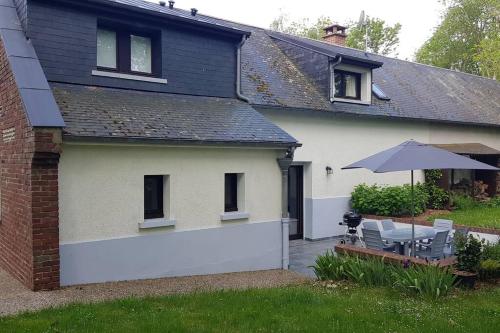 une maison blanche avec une table et un parasol dans l'établissement Gîte de la Hourdelière, au Hourdel coté baie, Cayeux-sur-mer, à Cayeux-sur-Mer