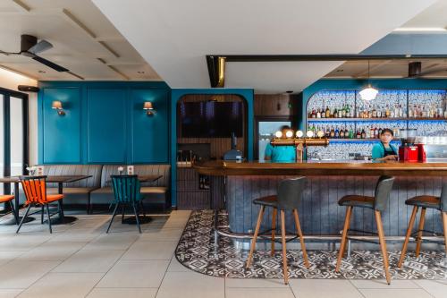 a bar in a restaurant with blue walls and chairs at The Dawin Hotel in Bangkok