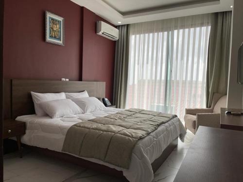 a bedroom with a large bed and a window at RESIDENCE SYCOMORE 1 in Abidjan