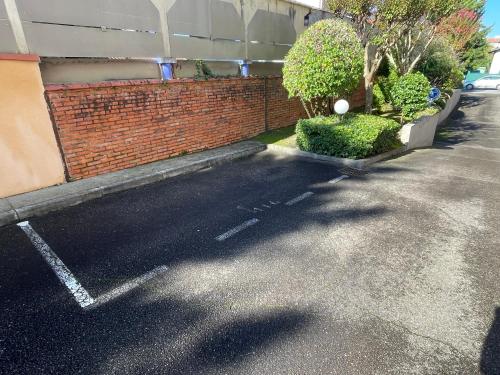 a parking lot next to a red brick building at Petit Charme - Balcon - Parking - Fibre in Dax