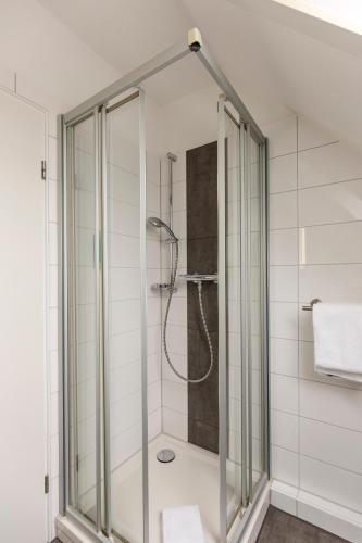 a shower with a glass door in a bathroom at Cuxlandhotel Studio 201 in Dorum-Neufeld