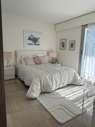 - une chambre blanche avec un grand lit et un oreiller rose dans l'établissement Manon B&B, à Roquebrune-Cap-Martin