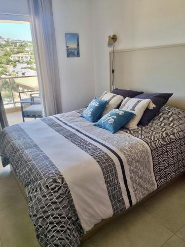 une chambre avec un lit avec des oreillers bleus et une fenêtre dans l'établissement Bel appartement neuf-4 personnes, à LʼÎle-Rousse