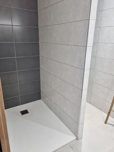 Elle comprend une douche avec un mur en carrelage blanc et gris. dans l'établissement Bel appartement neuf-4 personnes, à LʼÎle-Rousse