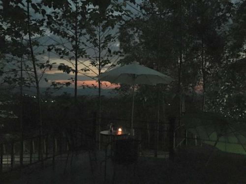 a table with a candle and an umbrella at night at Baan Rai Phufah Resort Chiangrai in Ban Pa Ruak