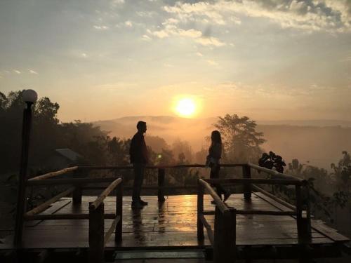 a man and a woman standing on a bridge looking at the sunset at Baan Rai Phufah Resort Chiangrai in Ban Pa Ruak