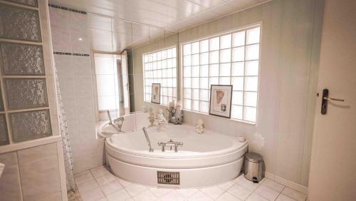 La salle de bains blanche est pourvue d'une baignoire et d'une fenêtre. dans l'établissement Gite74, Gite du MontBlanc, GLMB, à Saint-Gervais-les-Bains