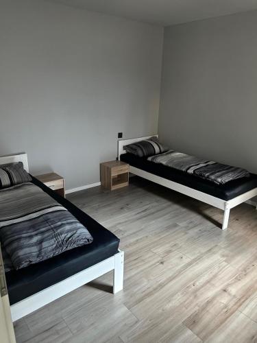 two beds in a room with wooden floors at Gemütliche Ferienwohnung mit 1 Schlafzimmer, Wohnzimmer mit Schlafcouch & voll ausgestattete Küche in Rauschenberg