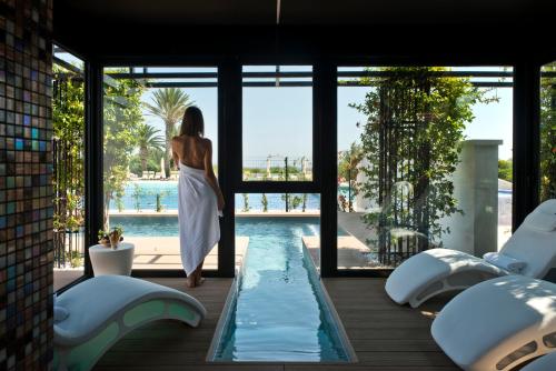 une femme en robe blanche debout à côté d'une piscine dans l'établissement Grand Hotel Masseria Santa Lucia, à Ostuni