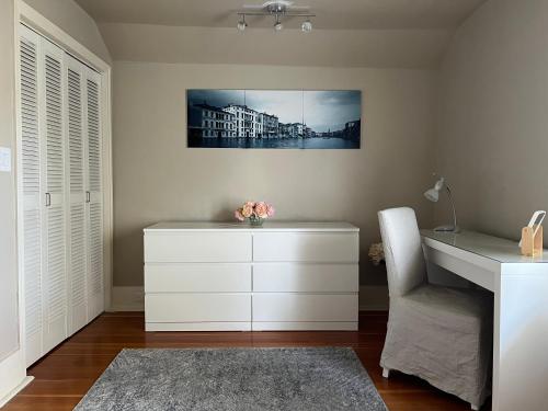 a room with a white dresser and a chair at Cozy homestay in the master bedroom of a River Heights home in Winnipeg