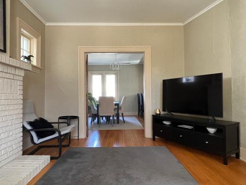 a living room with a television and a dining room at Cozy homestay in the master bedroom of a River Heights home in Winnipeg